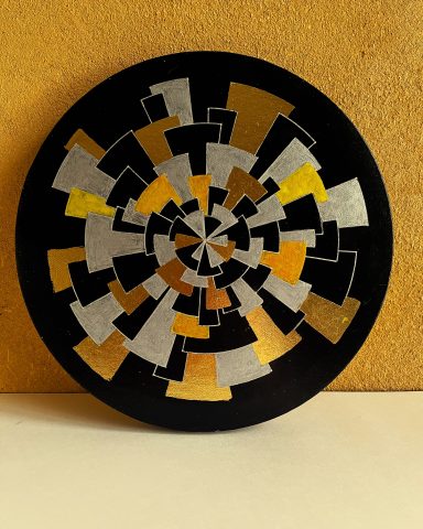 Cercle abstrait avec motifs géométriques en noir, argent, or et jaune.