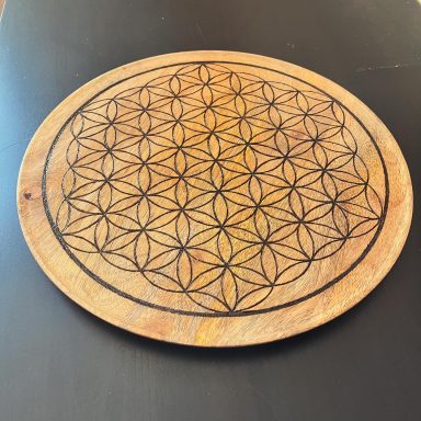 Planche en bois ronde gravée de motifs floraux géométriques.