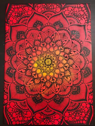 Motif mandala coloré en rouge et jaune sur fond noir, avec des motifs floraux détaillés.